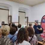 Ο ομιλητής, Δρ. Σιάσιος, στέκεται όρθιος και μιλάει σε μέρος του κοινού που έχει πλησιάσει μπροστά.