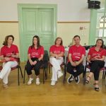 Ομάδα επτά ατόμων, πέντε γυναίκες και δύο άνδρες, καθισμένοι σε καρέκλες, φορώντας κόκκινα μπλουζάκια με το λογότυπο του συλλόγου αιμοδοτών.