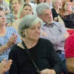 Κοντινό πλάνο σε μερικούς από τους παρευρισκόμενους, με μια γυναίκα να χειροκροτεί.