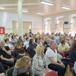 Πλάνο από το κέντρο του κοινού, με πολλούς παρευρισκόμενους να παρακολουθούν την εκδήλωση.