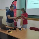 Ο Δρ. Σιάσιος παραλαμβάνει μια καφέ χάρτινη τσάντα από μια γυναίκα με κόκκινη μπλούζα του συλλόγου.